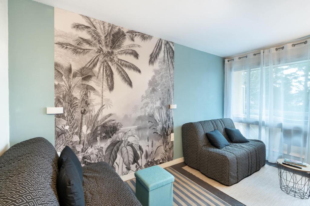 a living room with two chairs and a palm tree mural at Kersalé in Bénodet
