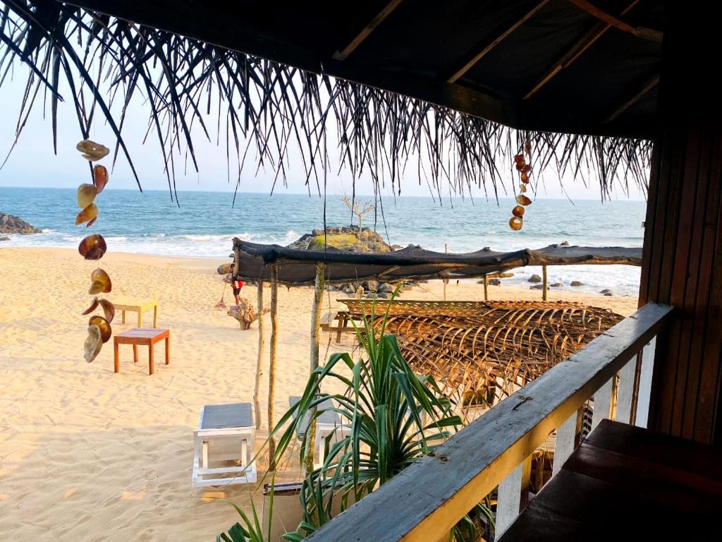 a beach with a straw umbrella and chairs and the ocean at Little Pumpkin Cabanas in Tangalle