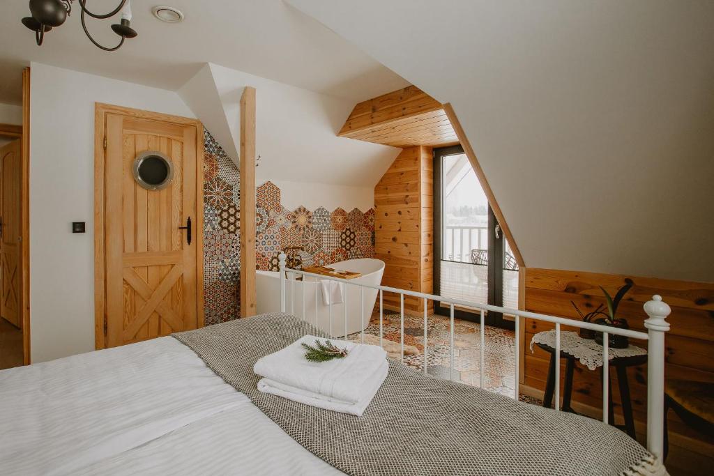 a bedroom with a bed and a bathroom with a tub at PUSZCZYKOWO siedlisko&spa in Białowieża