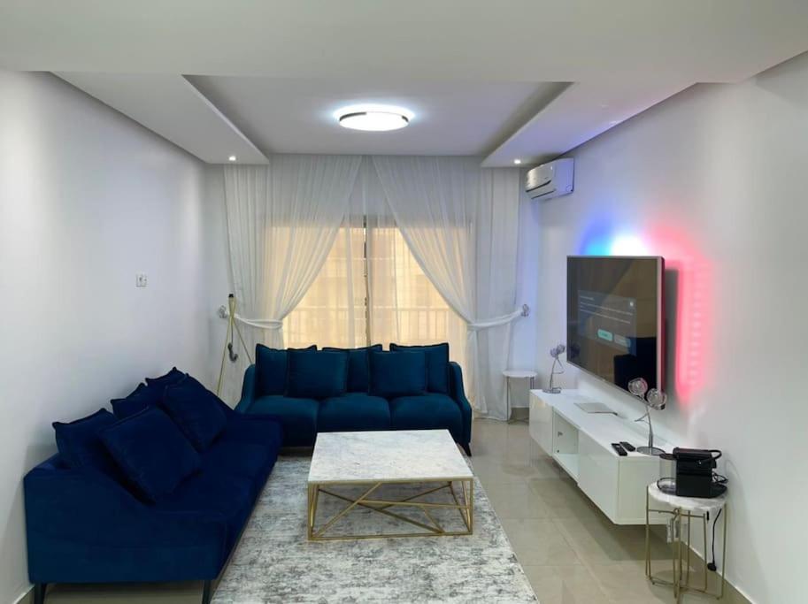 a living room with a blue couch and a tv at Appartement F3 Cité de l’Émergence Dakar Plateau in Dakar