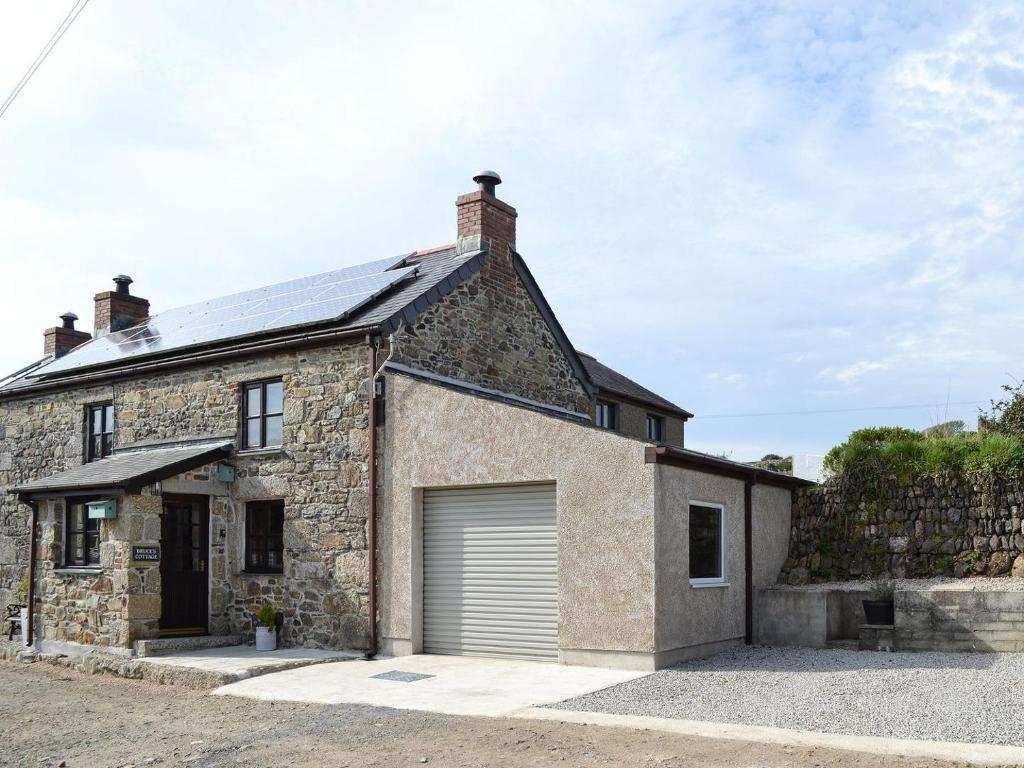 een oud stenen huis met een garage bij Bruces Cottage in Saint Erth