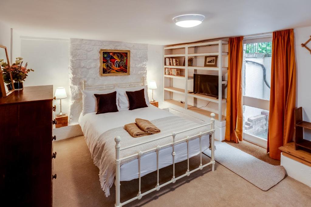 Schlafzimmer mit einem weißen Bett und einem TV in der Unterkunft The Summertown STUDIO 1BR & kitchenette in Oxford