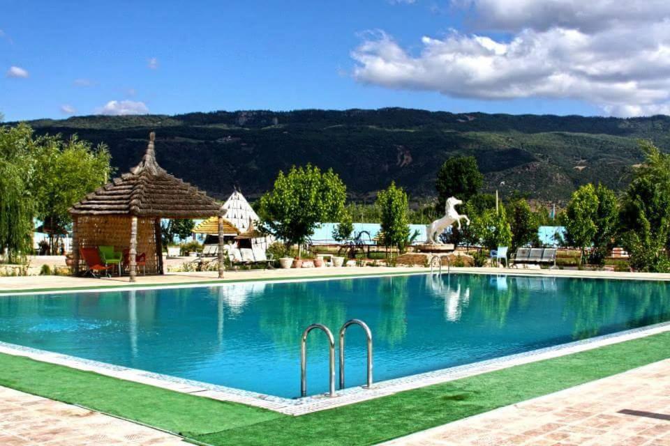 una piscina en un complejo con una montaña en el fondo en Le Vallon Vert - Club Equestre, en Azrou