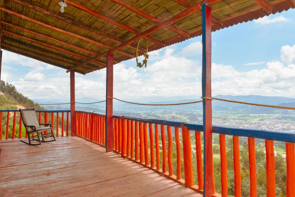 una terraza de madera con una silla en la cima de una montaña en MIRADOR DE MARCURA, en Paipa