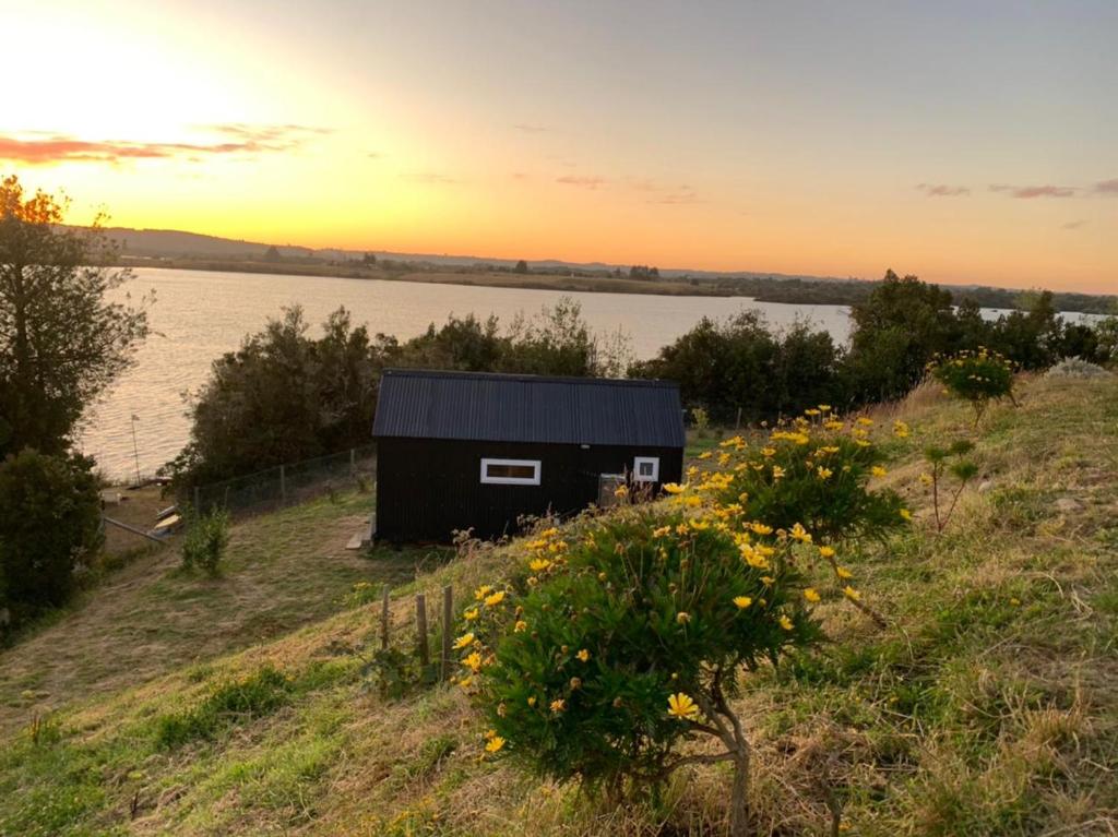 uma cabana preta numa colina ao lado de um corpo de água em Cabaña 7 Islas em Ilque