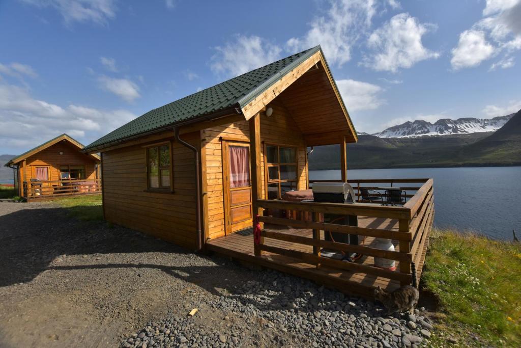 een houten hut aan de oever van een meer bij Sólbrekka Holiday Homes in Mjóifjörður