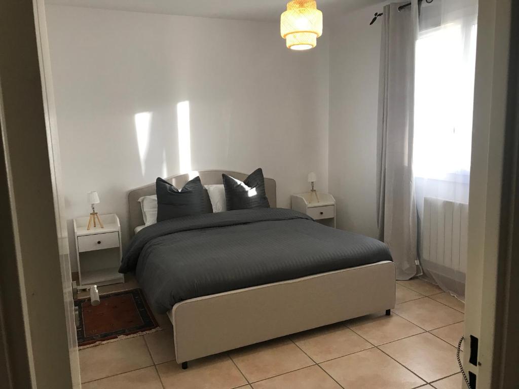 una camera da letto con un letto con cuscini neri e una finestra di Résidence privée calme 15 min à pied du centre parking gratuit a Arles