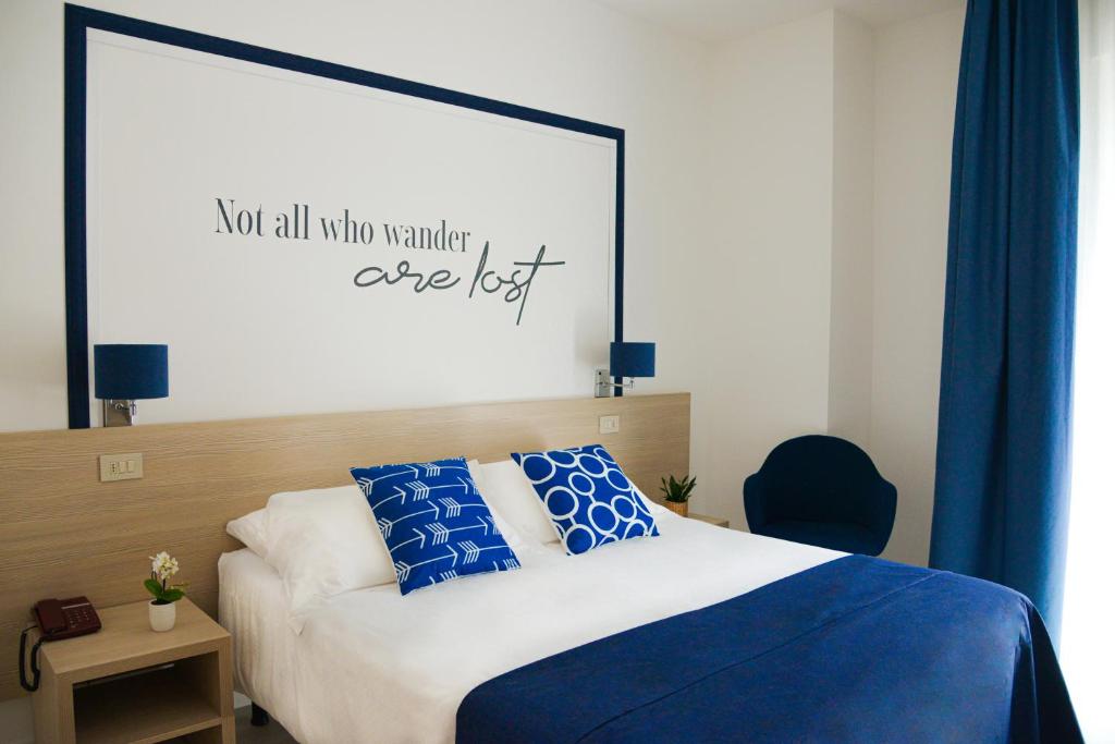 a bedroom with a bed with a sign that reads not all who wander are lost at Hotel Renania in Bibione