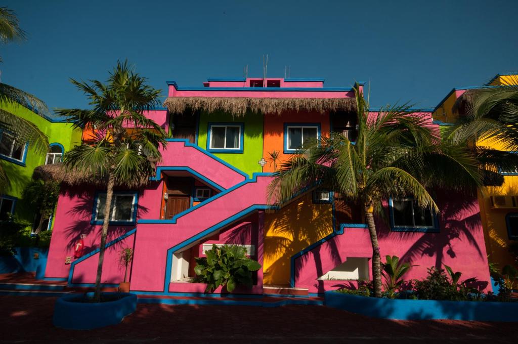 un edificio colorido con palmeras delante en Del Sol Beachfront, en Akumal