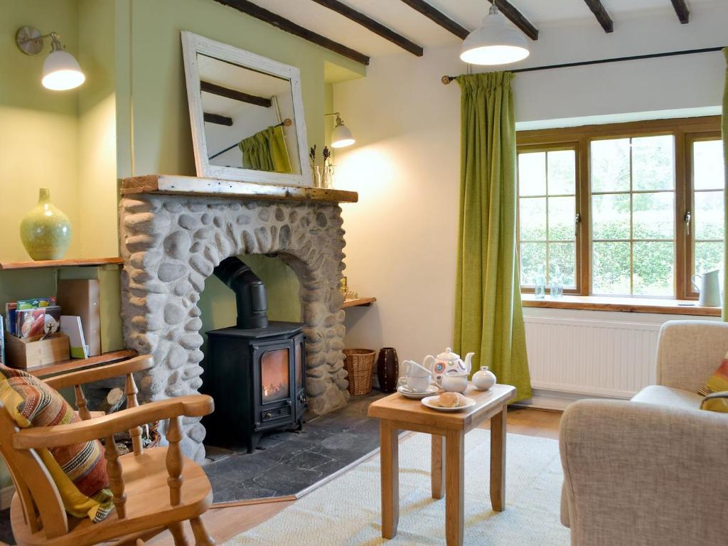 a living room with a stone fireplace with a mirror at Bryn Heulog in Penclawdd