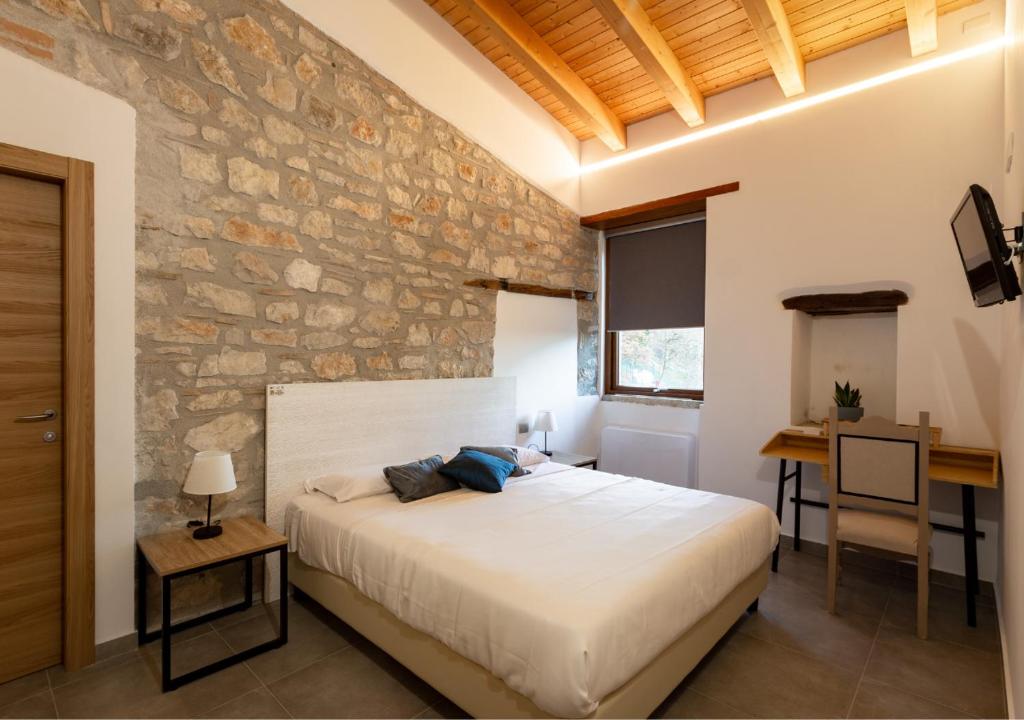a bedroom with a bed and a stone wall at Tenuta San Martino in Nusco