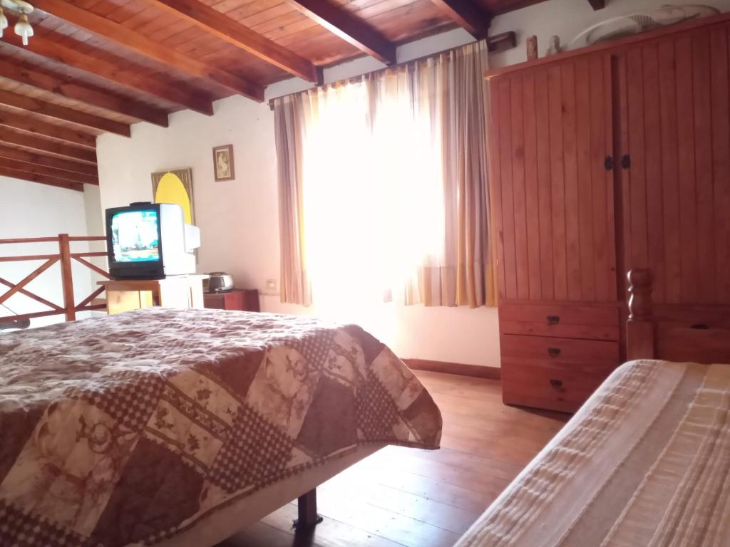 1 dormitorio con 1 cama, TV y ventana en Amplia casa con estacionamiento cerca del mar en Mar de Ajó