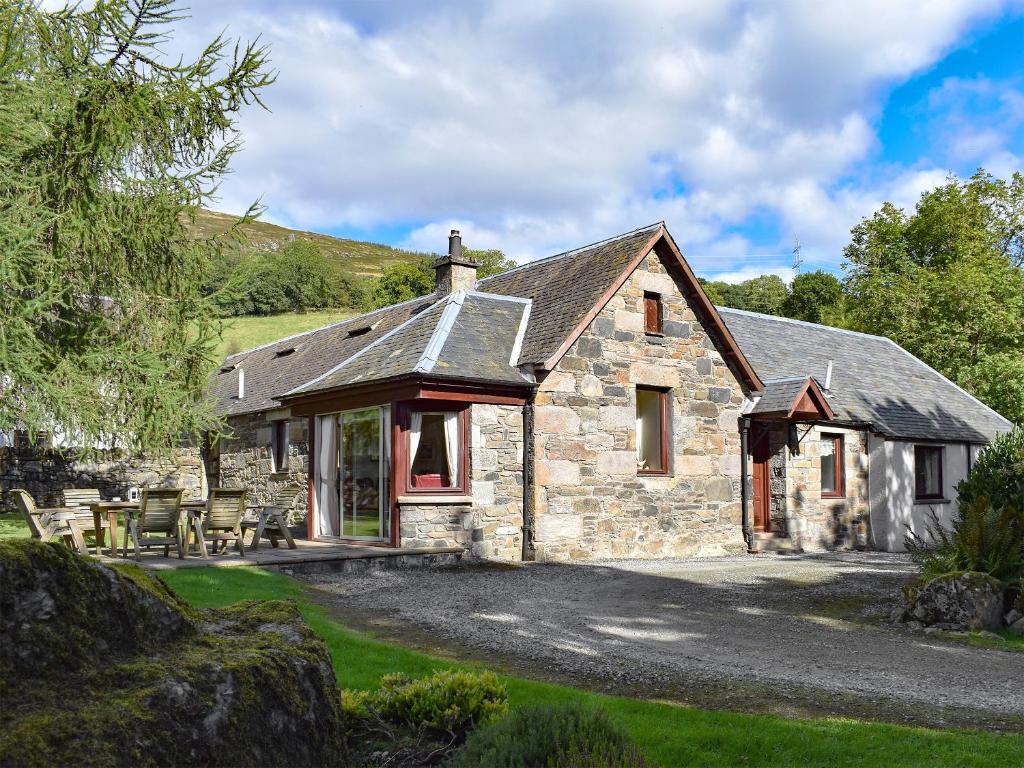 una casa de piedra con mesas y sillas delante de ella en Tigh Na Bruaich, en Kenmore