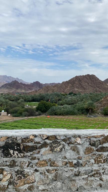 a stone wall with a view of a field and mountains at Alhara Lodge استراحة الحارة 