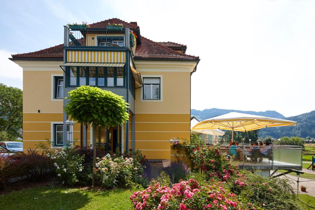 a yellow house with a table and an umbrella at Gasthof Schattleitner in Brückl