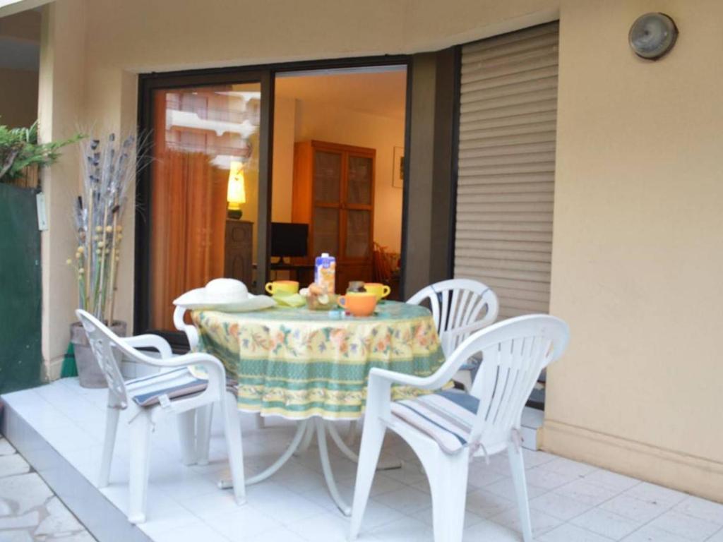 einen Tisch mit 3 Stühlen und einen Tisch mit einer Schüssel Essen in der Unterkunft Appartement Fréjus, 2 pièces, 4 personnes - FR-1-226A-56 in Fréjus