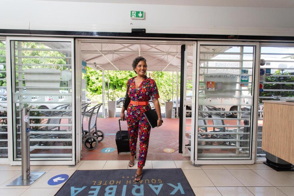 a woman standing in front of a glass door at Karibea Squash Hôtel in Fort-de-France