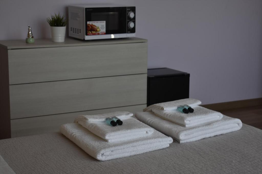 dwa stosy ręczników siedzące na łóżku z kuchenką mikrofalową w obiekcie Villa Giulini Rho w mieście Rho