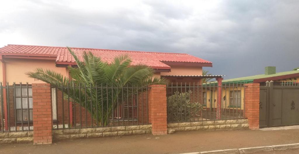 een huis met een hek en een palmboom bij Feel at home stay in Bloemfontein