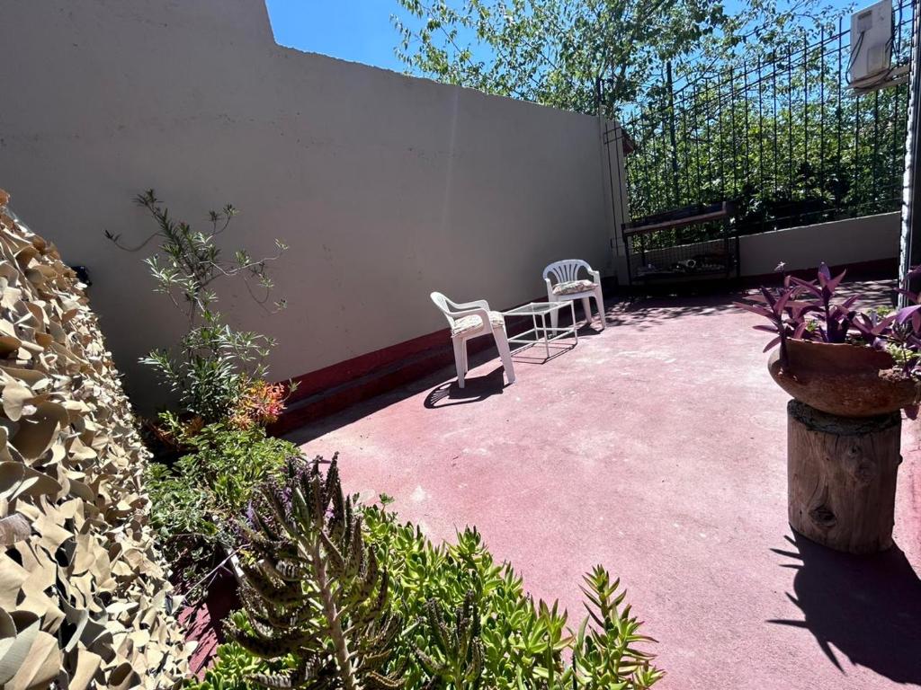 un patio con 2 sillas blancas y plantas en Apartamento en Mendoza en Mendoza