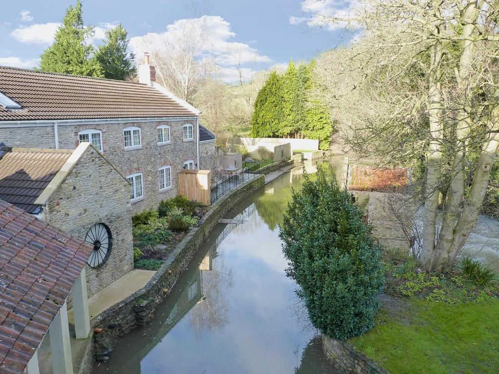 a river in the middle of a city with a bridge at Herons Weir in Buckland Dinham