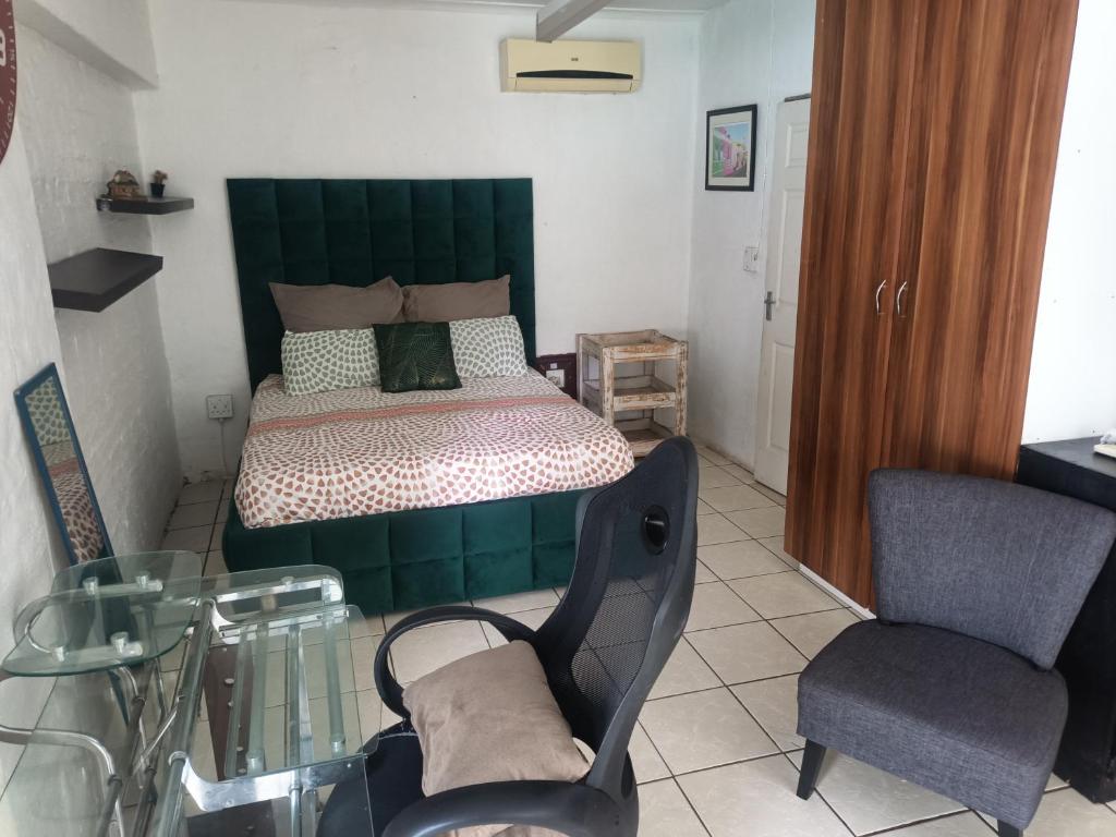 1 dormitorio con 1 cama, mesa de cristal y silla en Trinity Cottage, en Vanderbijlpark