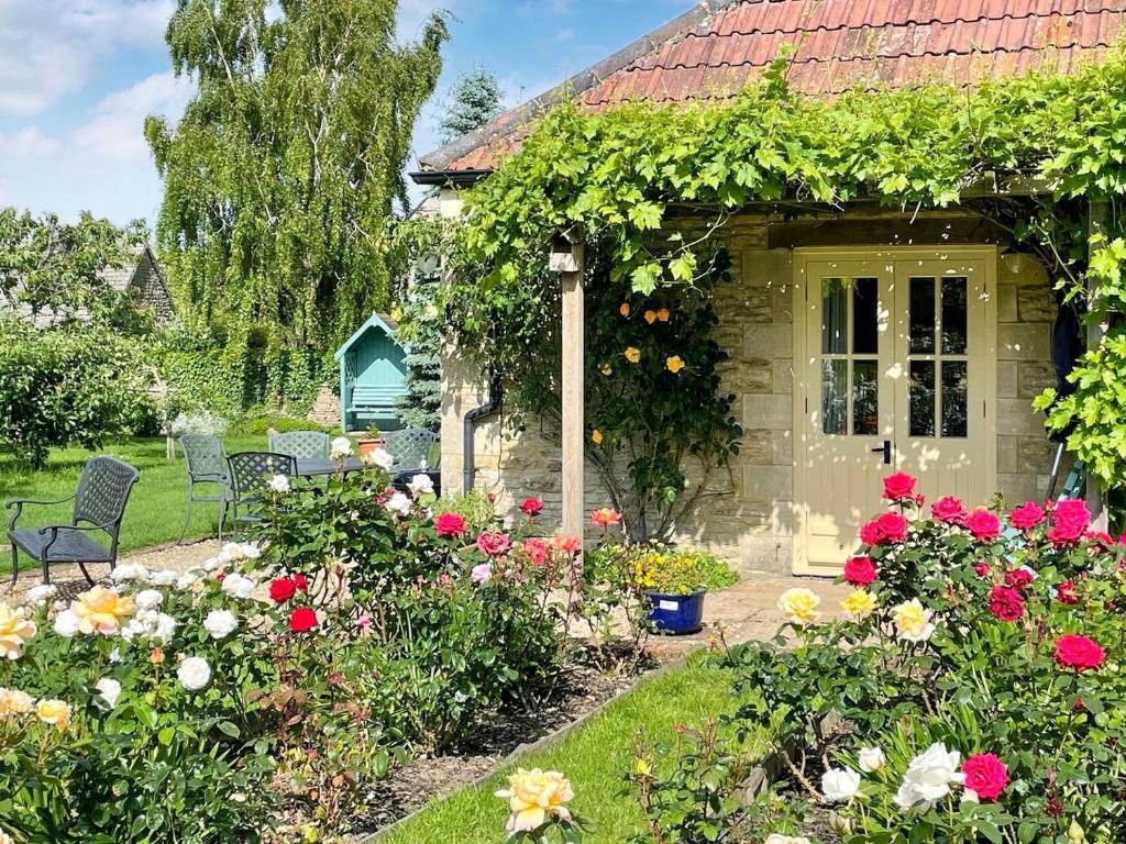a house with a bunch of flowers in the yard at Le Jardin in Rodmarton