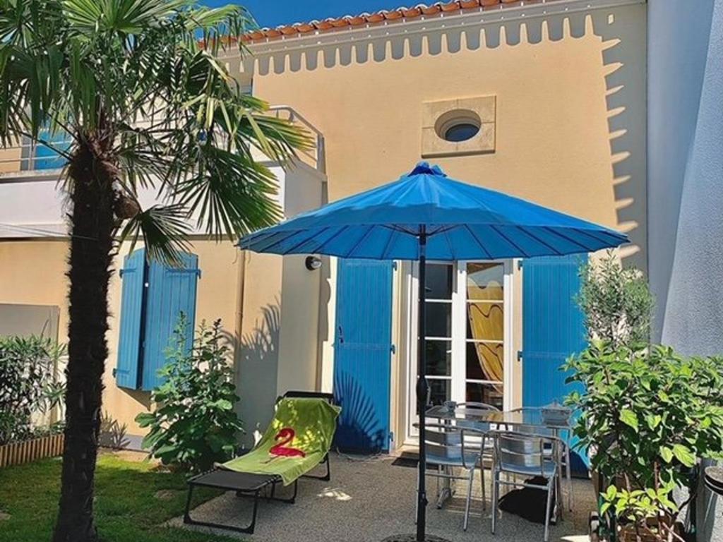 a blue umbrella sitting next to a table and chairs at Maison Châtelaillon-Plage, 3 pièces, 6 personnes - FR-1-246-552 in Châtelaillon-Plage