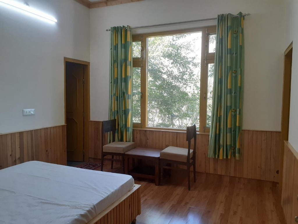 a bedroom with a bed and a window and a desk at Gazing Moon Homestay in Shamshi