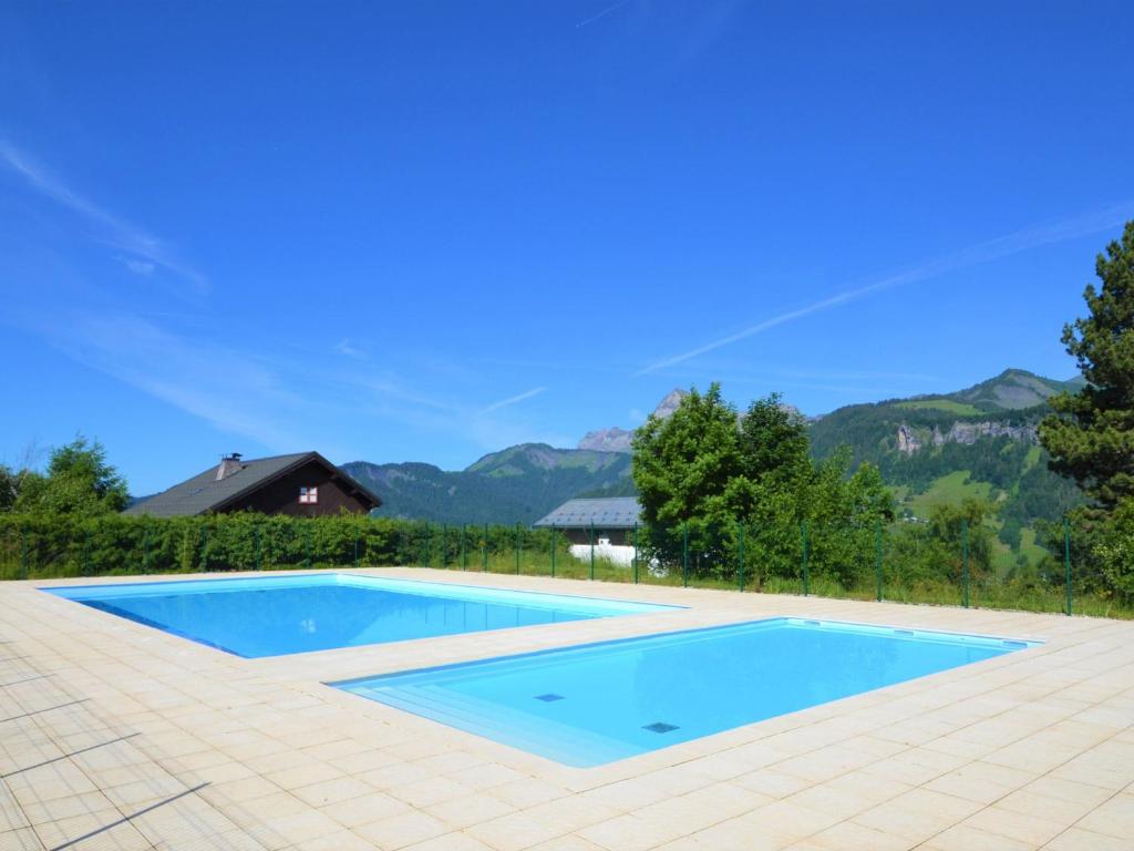 a large swimming pool with a tile floor and mountains in the background at Studio Notre-Dame-de-Bellecombe, 1 pièce, 2 personnes - FR-1-505-48 in Notre-Dame-de-Bellecombe