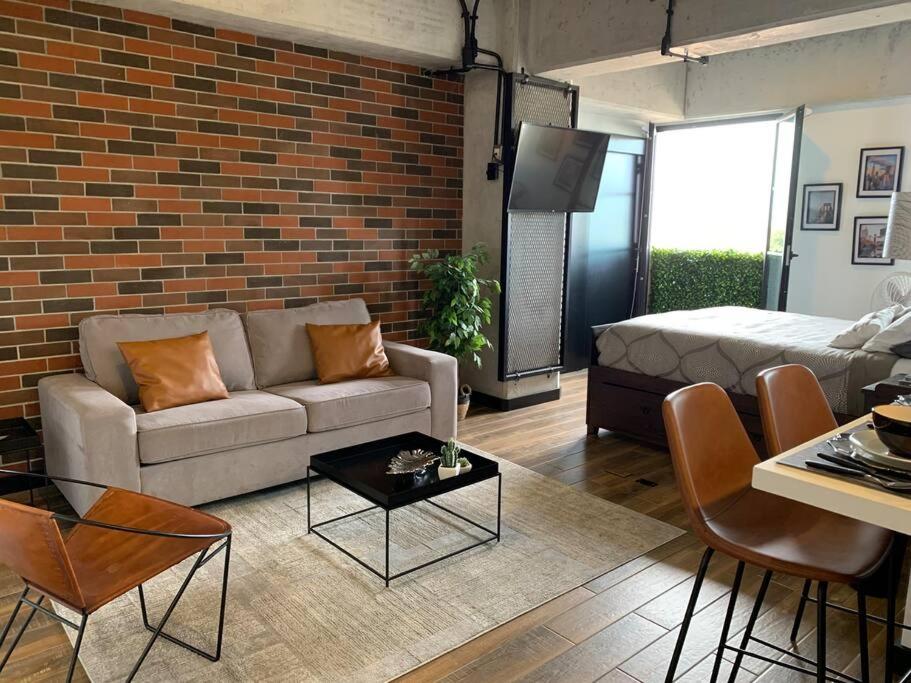 a living room with a couch and a brick wall at Apartamento de lujo, MODERNO estilo NEW YORK in Guatemala