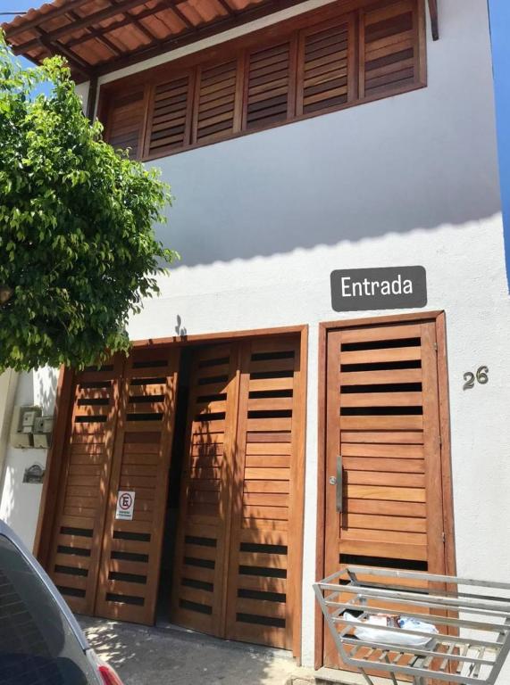 un bâtiment avec des portes en bois et un panneau indiquant Emigrada dans l'établissement Suítes Praia de Pajuçara, à Maceió