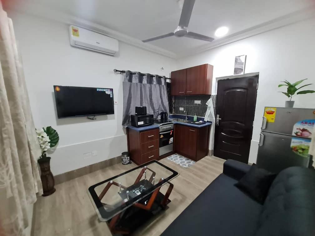a living room with a kitchen with a black refrigerator at NESTA BARRON -Home Away from Home in North Legon