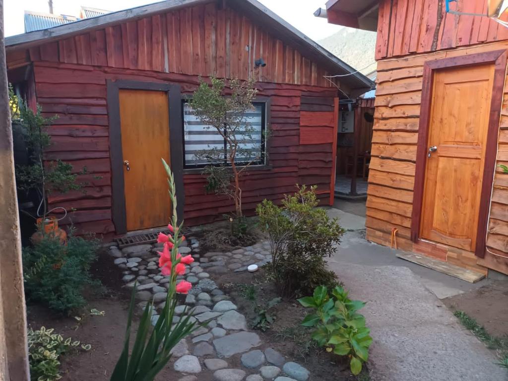 a log cabin with a door and flowers in front of it at Cabañas Érica in Choshuenco