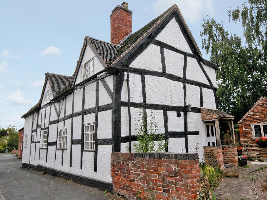 an old white and black building with a chimney at Swiss Cottage - E5375 in Alrewas