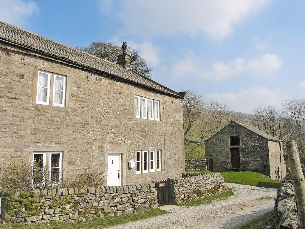 an old stone house with a stone wall at Angram Farmhouse in Deepdale