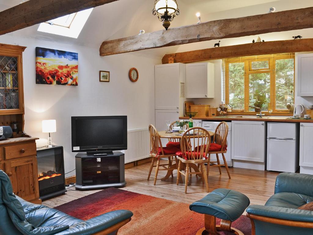 a living room with a television and a table with chairs at High House Holiday Cottages 1 in Hooe