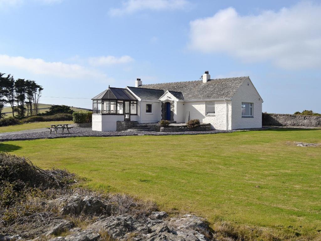 een wit huis op het strand met een grote tuin bij Bwthyn Pereos in Llanrhwydrys