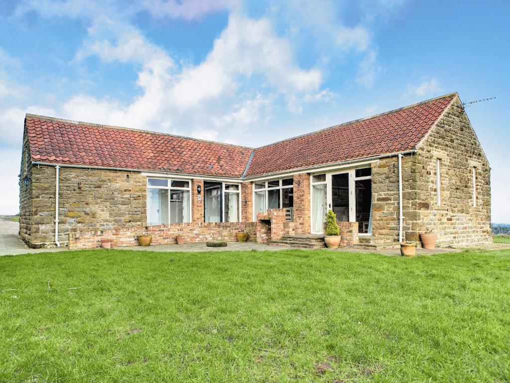 a brick house with a green lawn in front of it at Blue Mountain Barn in Scalby