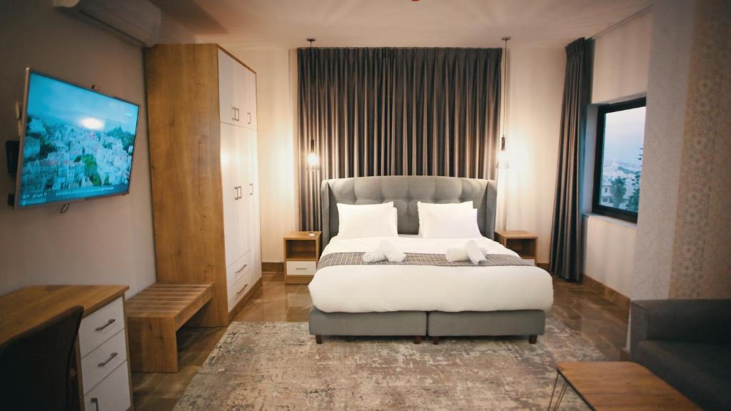 - une chambre avec un grand lit et une télévision à écran plat dans l'établissement Lotus Boutique Hotel, à Bethléem