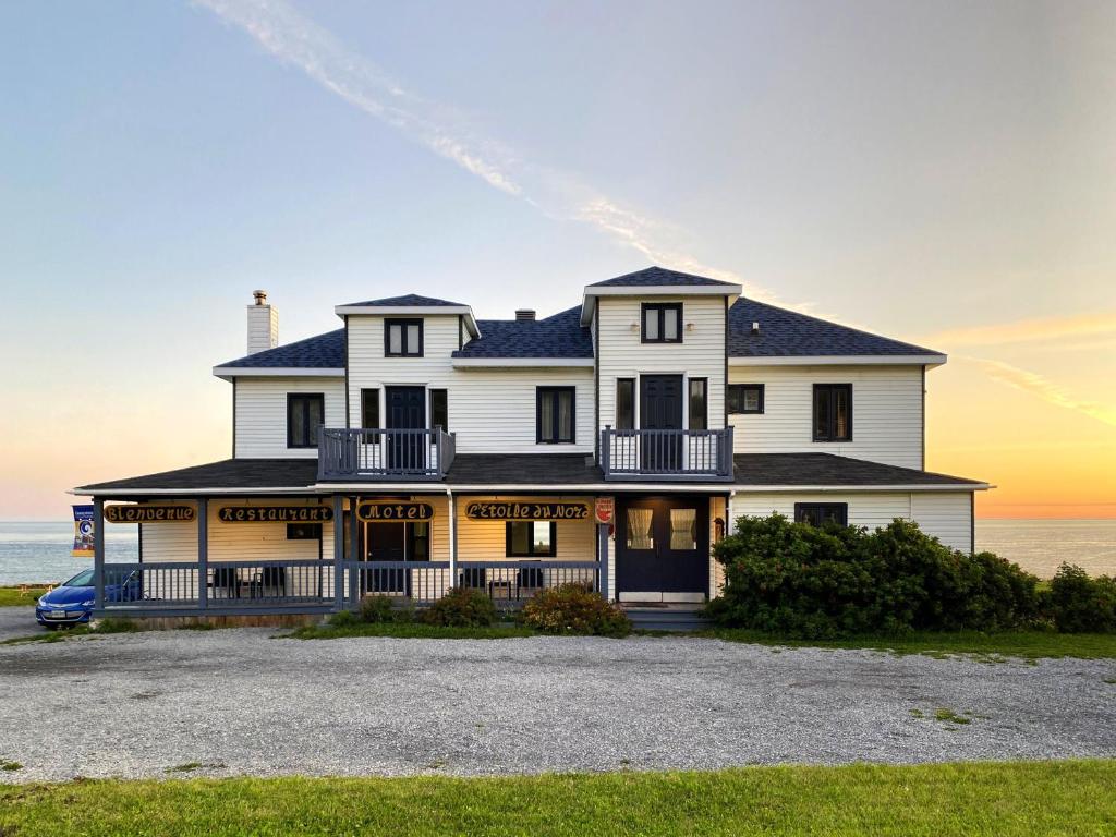 een groot wit huis met de oceaan op de achtergrond bij Restaurant-Motel L'Etoile du Nord in Pointe a la Fregate