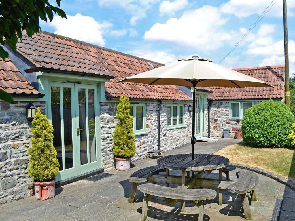 eine Terrasse mit einem Sonnenschirm, einem Tisch und Stühlen in der Unterkunft Bluebell Cottage - E4741 in Chipping Sodbury