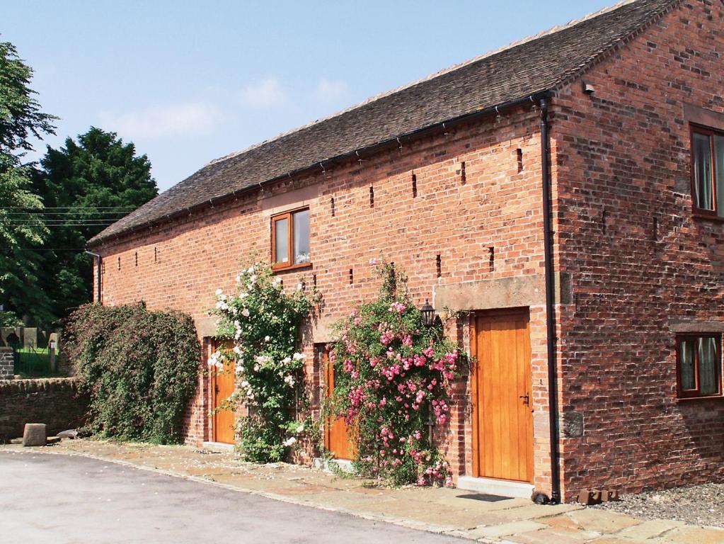 a brick building with flowers on the side of it at Tythe Barn in Kingsley