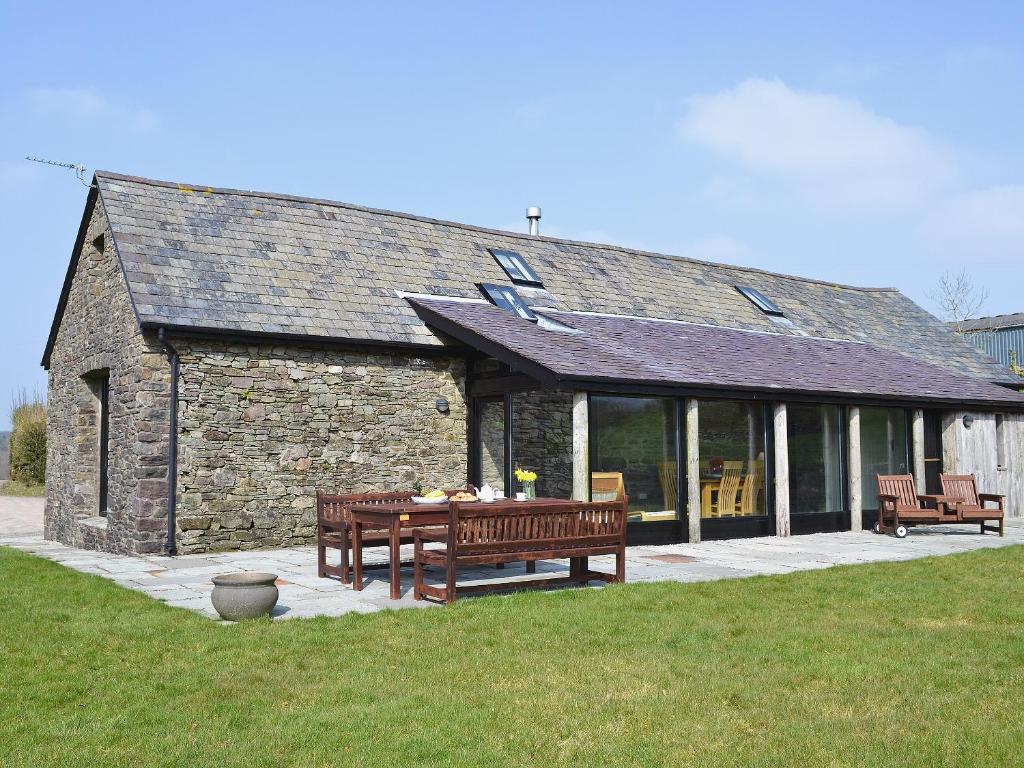 a stone building with two benches in front of it at Cennen Cottages- Longhouse in Ffair-fâch