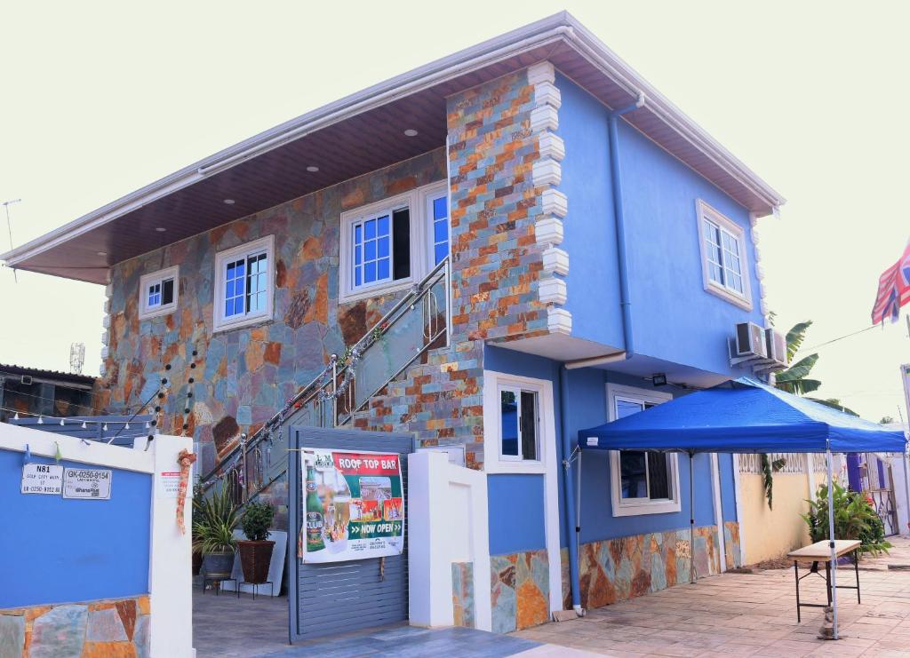 a blue building with an umbrella in front of it at Lady M guest House in Tema