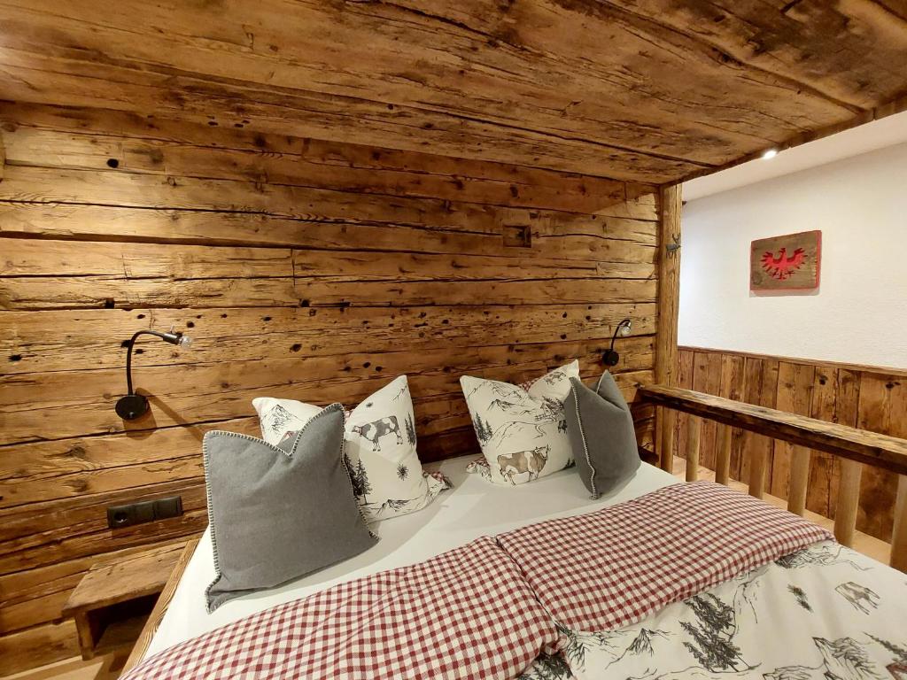 a bedroom with wooden walls and a bed with pillows at Wieserhof Tirol in Oetz