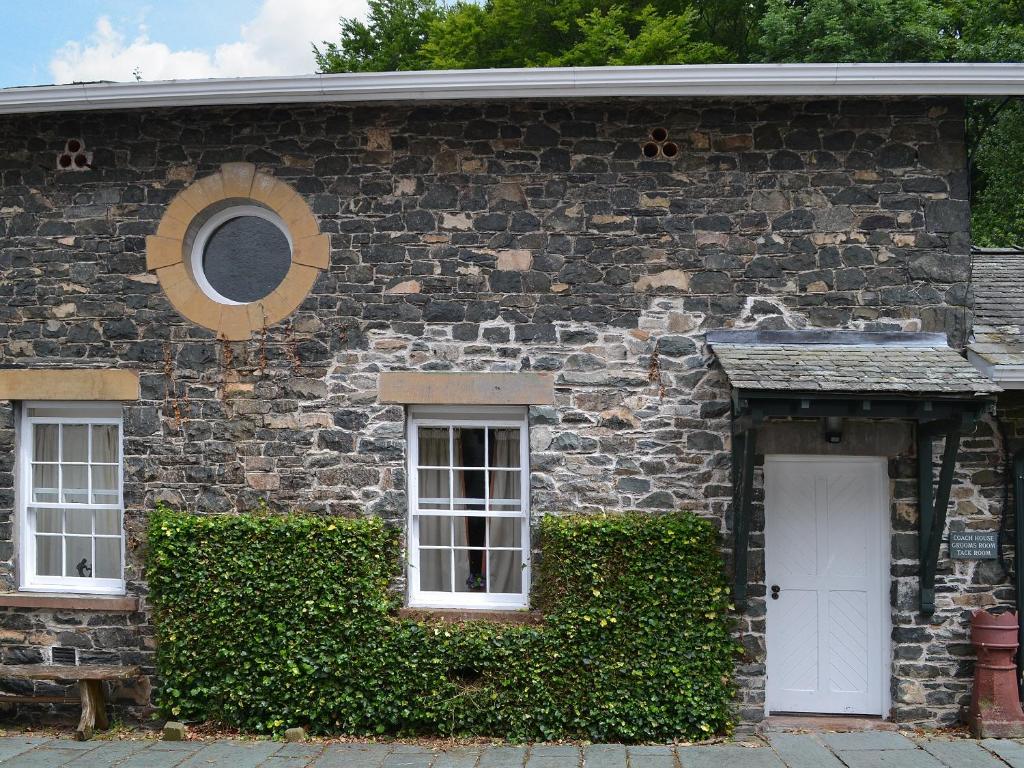 uma casa de pedra com duas janelas e uma porta branca em Grooms Room em Thirlmere