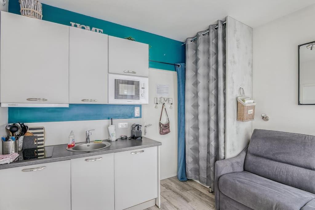 una cocina con fregadero y un sofá en una habitación en Saint-Malo intramuros - Port à 30M et plage à 200M, en Saint-Malo