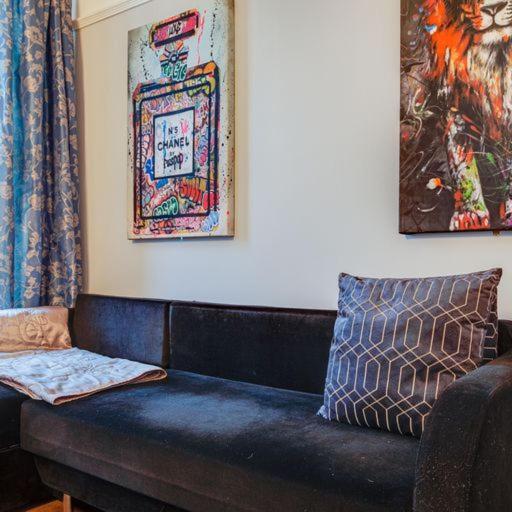 a black couch in a living room with paintings at Somerset House in Bangor