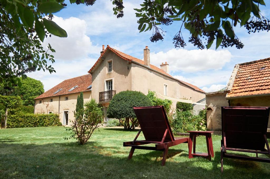 熱夫雷尚貝爾坦的住宿－Maison Laroze，两把椅子坐在房子前面的草上